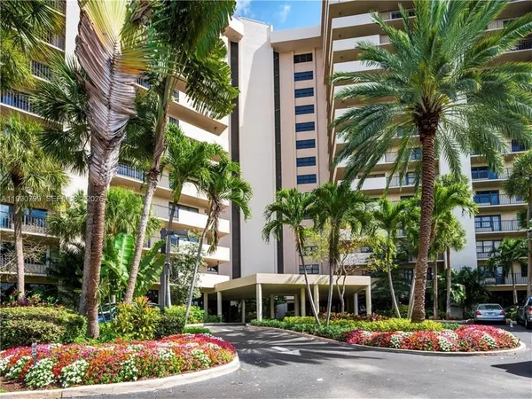 a front view of multi story residential apartment building with yard and green space