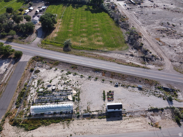 345 North Main Street Clawson, UT 84516 - Photo 4 of 17 Expansive property featuring a large greenhouse structure, a white-sided building with a dark roof, and a gravel lot