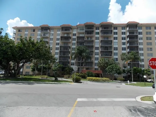 a front view of multi story residential apartment building with yard and traffic signal
