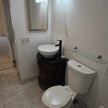 a white toilet sitting next to a bathroom sink and a mirror