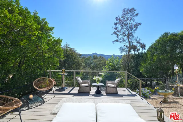 a view of a roof deck with table and chairs potted plants with wooden floor and fence