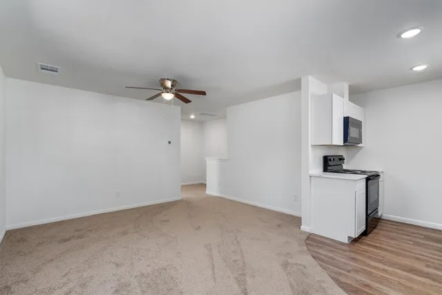a view of a kitchen with a sink a ceiling fan and stainless steel appliances
