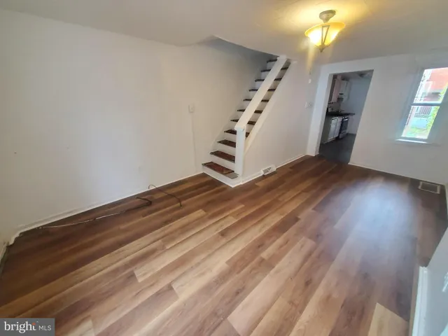 a view of an empty room with wooden floor and staircase