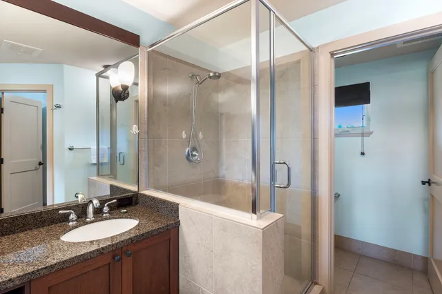 a bathroom with a granite countertop sink mirror and shower