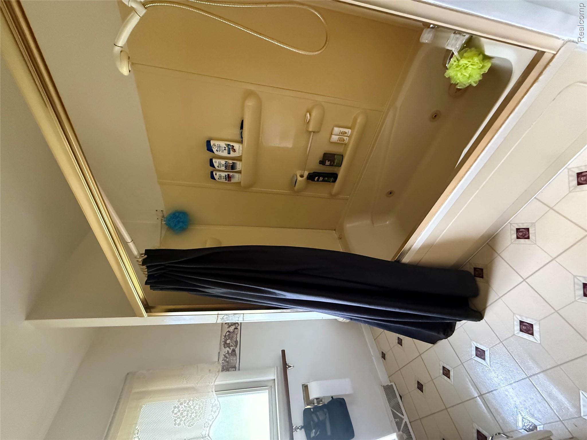 6526 State Road Millington, MI 48746 - Photo 10 of 29 Jetted tub with a wall-mounted shower head, surrounded by a light-colored shower enclosure
