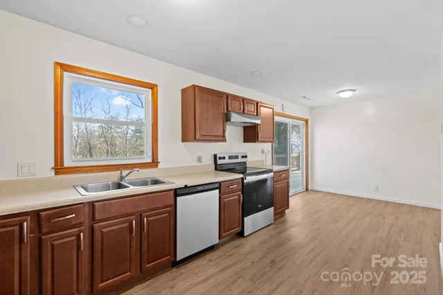 a kitchen with stainless steel appliances granite countertop a sink cabinets and wooden floor
