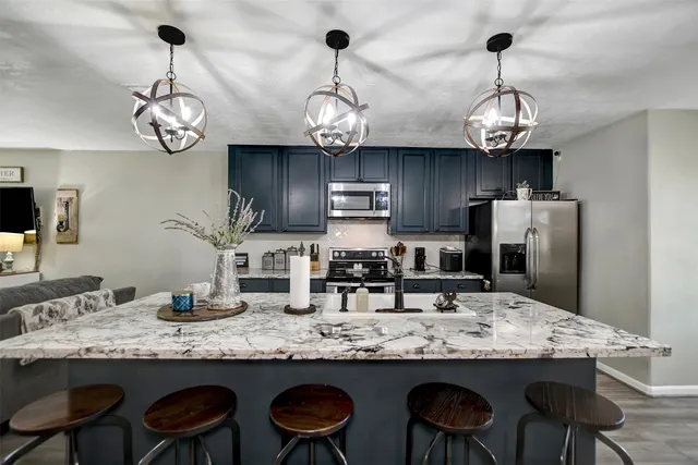 a kitchen with stainless steel appliances granite countertop a sink a stove and chairs