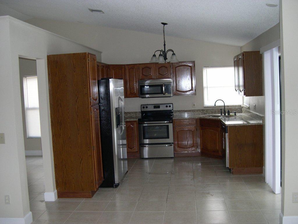 1437 East Amanda Road Kissimmee, FL 34744 - Photo 5 of 12 a kitchen with stainless steel appliances granite countertop a refrigerator a stove a sink and a microwave
