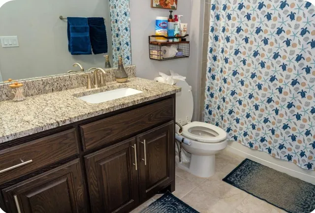 a bathroom with a granite countertop toilet sink and mirror