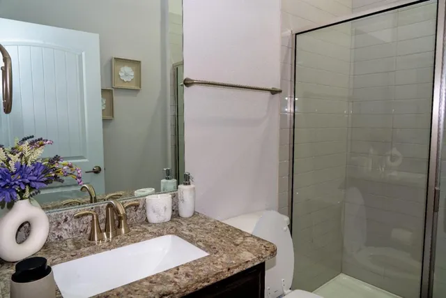 a bathroom with a granite countertop shower a sink and a mirror