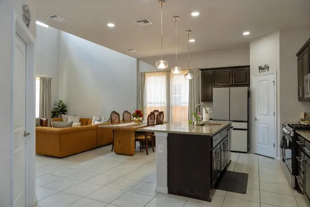a living room with couches kitchen view and a refrigerator