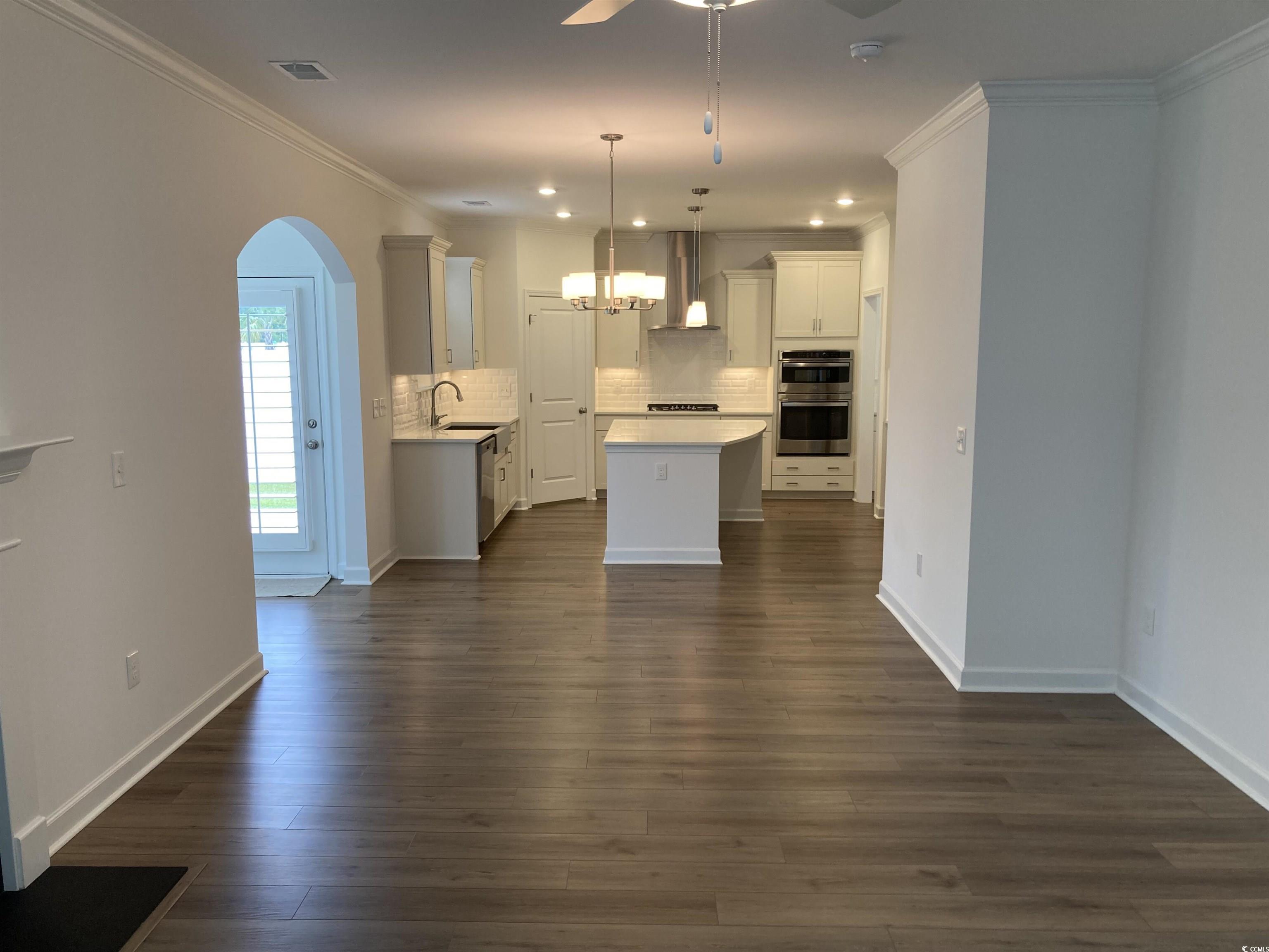 736 Enchantment Loop Myrtle Beach, SC 29588 - Photo 24 of 39 Kitchen featuring ornamental molding, a kitchen island, decorative backsplash, decorative light fixtures, and white cabinets
