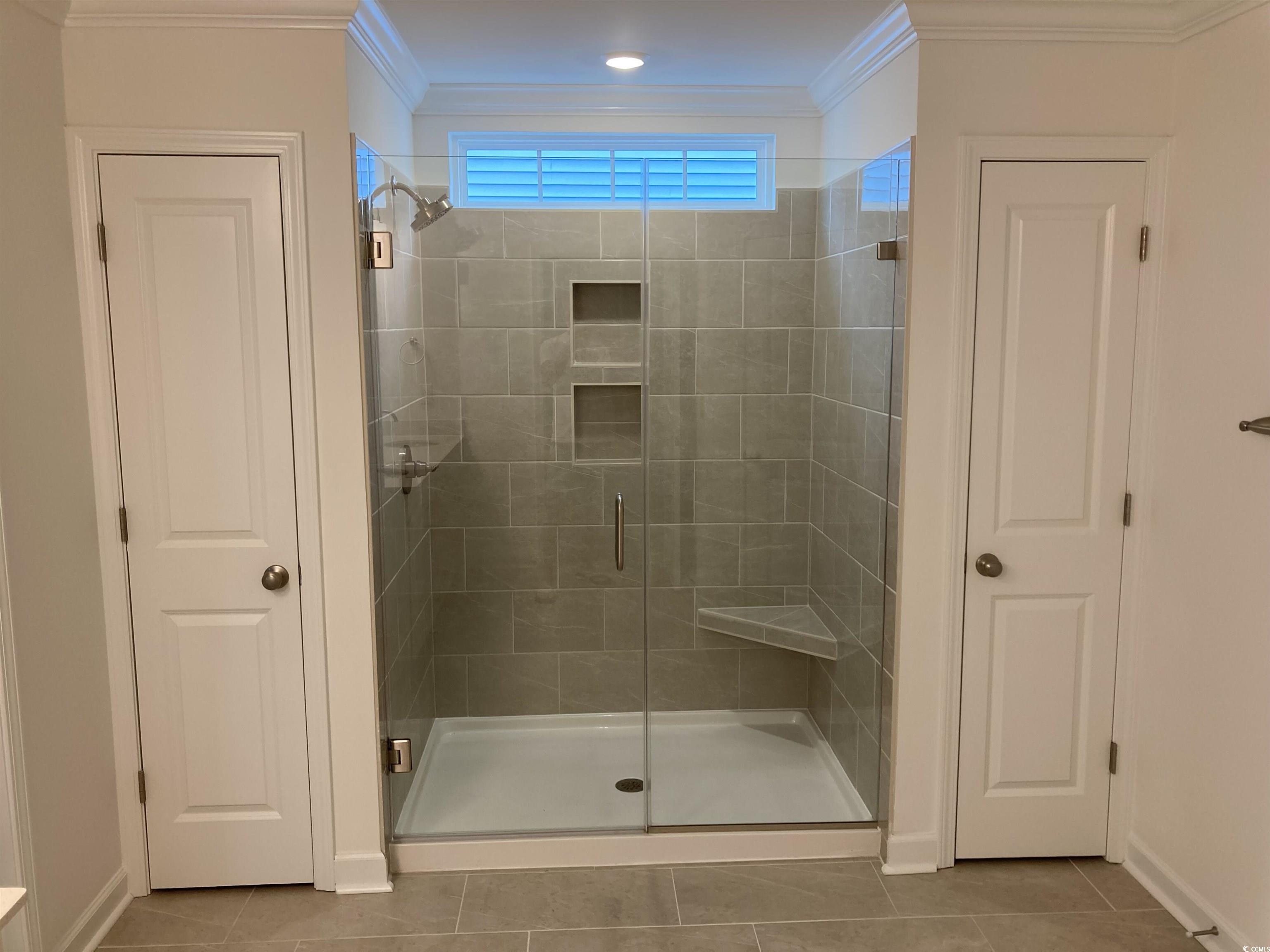 736 Enchantment Loop Myrtle Beach, SC 29588 - Photo 34 of 39 Full bathroom featuring a closet, a shower stall, light tile patterned floors, and crown molding