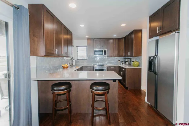 a kitchen with stainless steel appliances granite countertop a refrigerator a stove a sink and a refrigerator with wooden floor