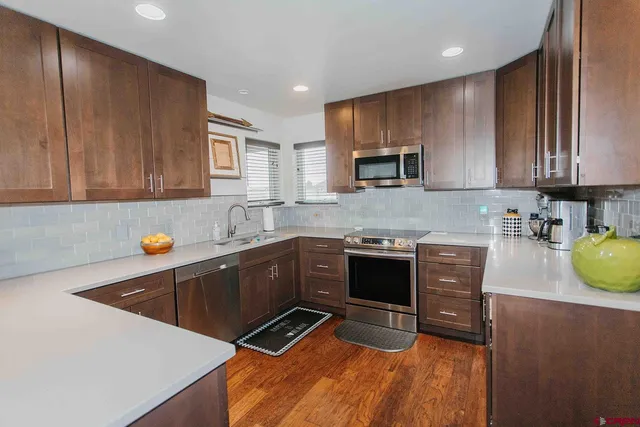 a kitchen with stainless steel appliances a stove a sink a microwave a refrigerator and cabinets