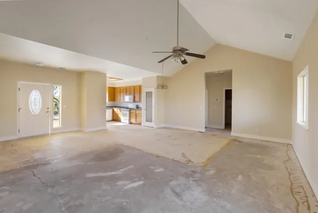 an empty room with a chandelier fan and windows