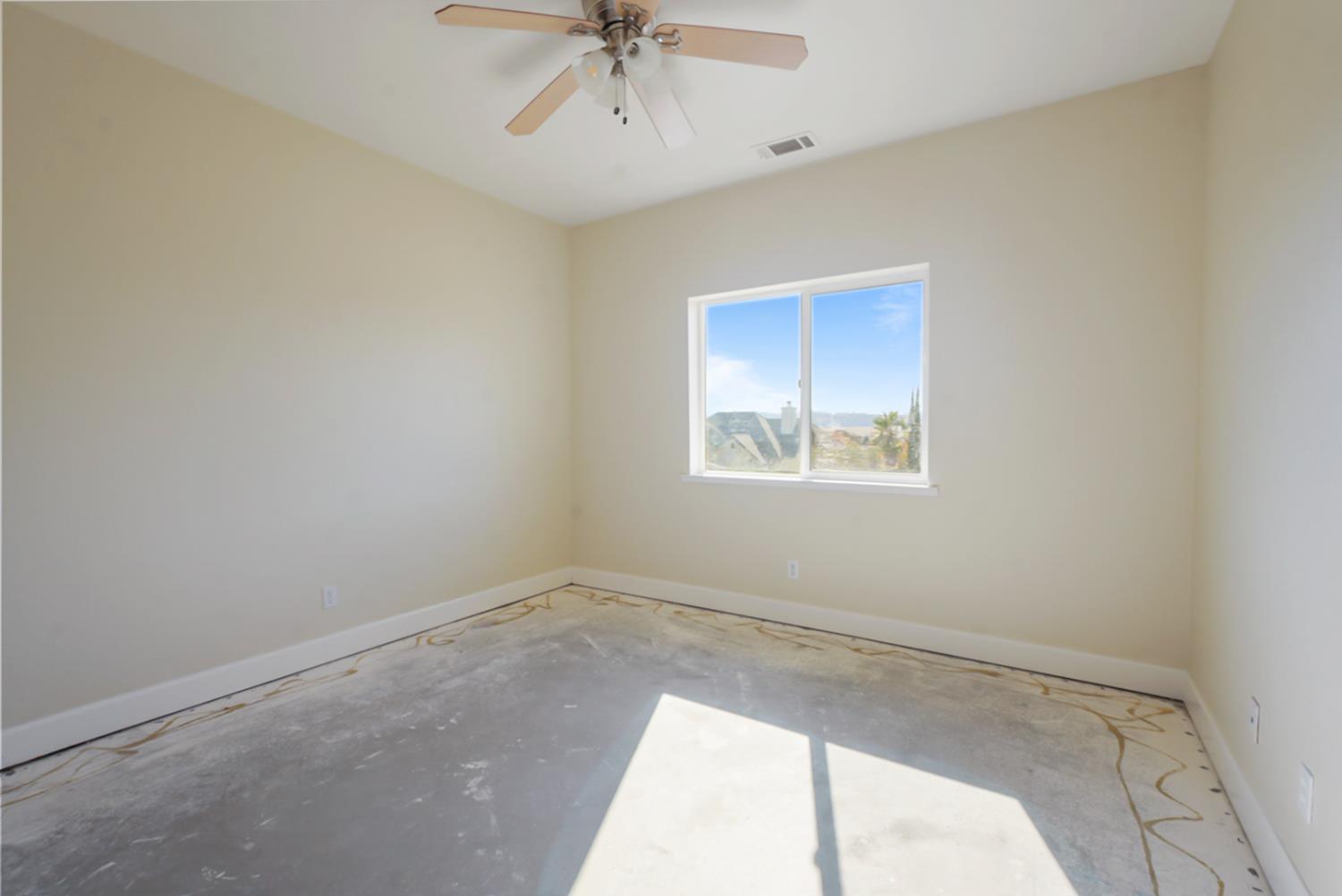 3493 Quail Hill Road Copperopolis, CA 95228 - Photo 16 of 38 an empty room with a chandelier fan and windows
