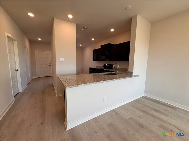 a living room with stainless steel appliances kitchen island furniture a flat screen tv and a sink