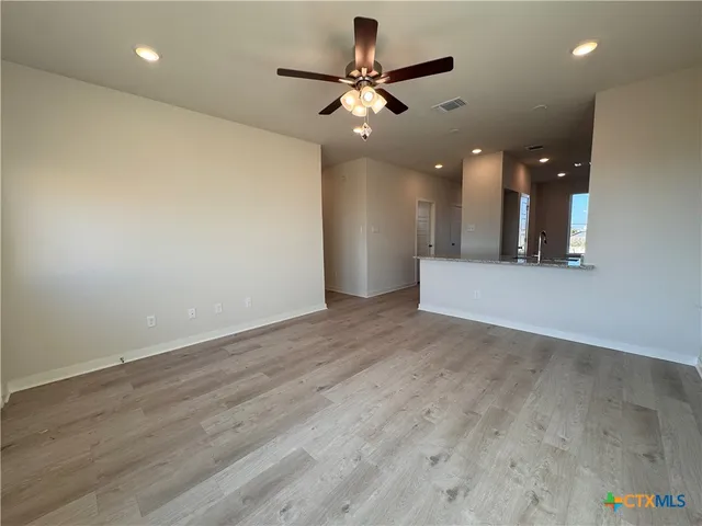 an empty room with wooden floor and a ceiling fan
