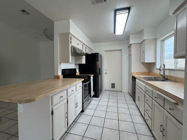 a large kitchen with a stove top oven a sink dishwasher and a refrigerator