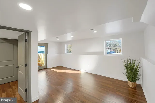 a view of an empty room with wooden floor and windows