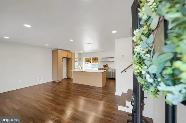 a view of kitchen with stainless steel appliances a large counter top a sink and a wooden floor