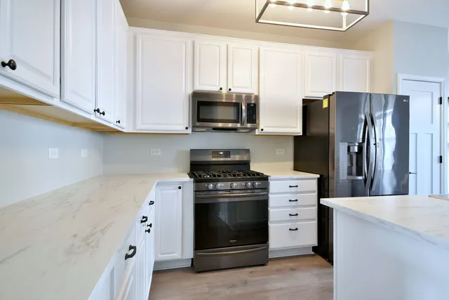 a kitchen with stainless steel appliances white cabinets and a stove a refrigerator with wooden floor