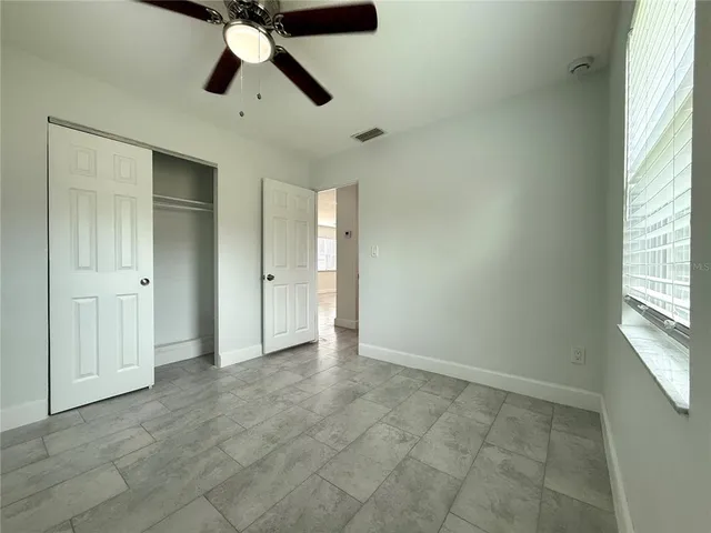 a view of an empty room and window and chandelier fan