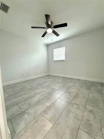 an empty room with a ceiling fan and window