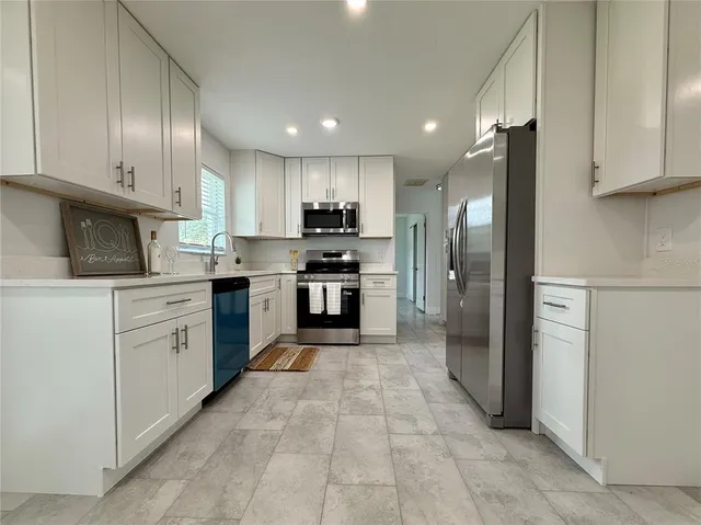 a large kitchen with stainless steel appliances granite countertop a stove a sink and a refrigerator