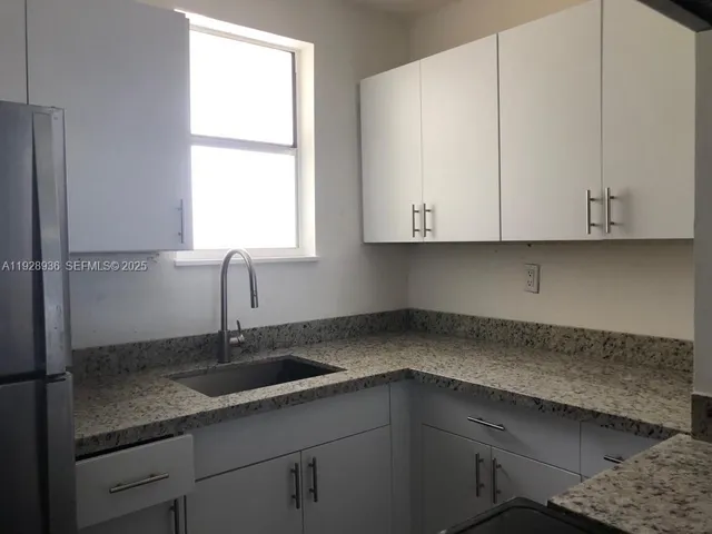 a kitchen with granite countertop white cabinets and a sink