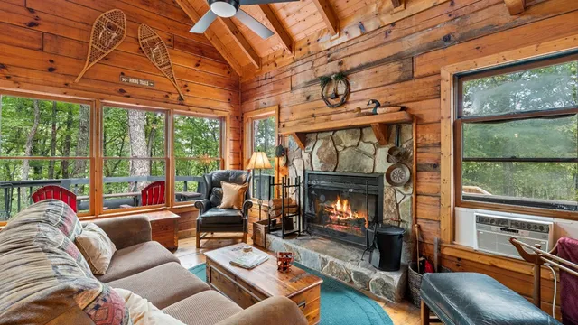 a living room with furniture a fireplace and floor to ceiling windows