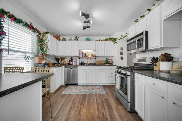 a kitchen with granite countertop a sink cabinets stainless steel appliances and a window
