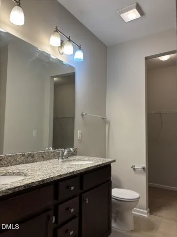 a bathroom with a granite countertop sink a toilet and a mirror