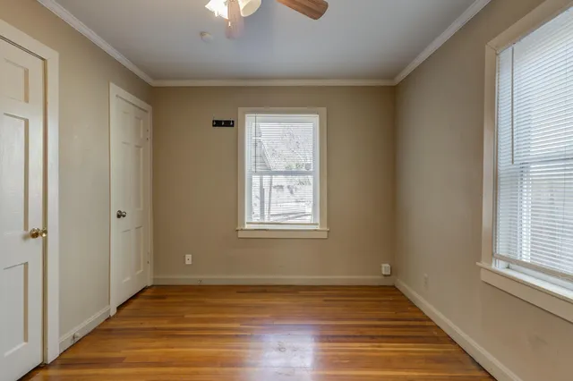 a view of an empty room with wooden floor closet and a window