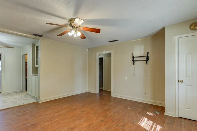 a view of an empty room with window and wooden floor
