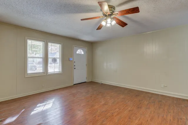 an empty room with windows and fan
