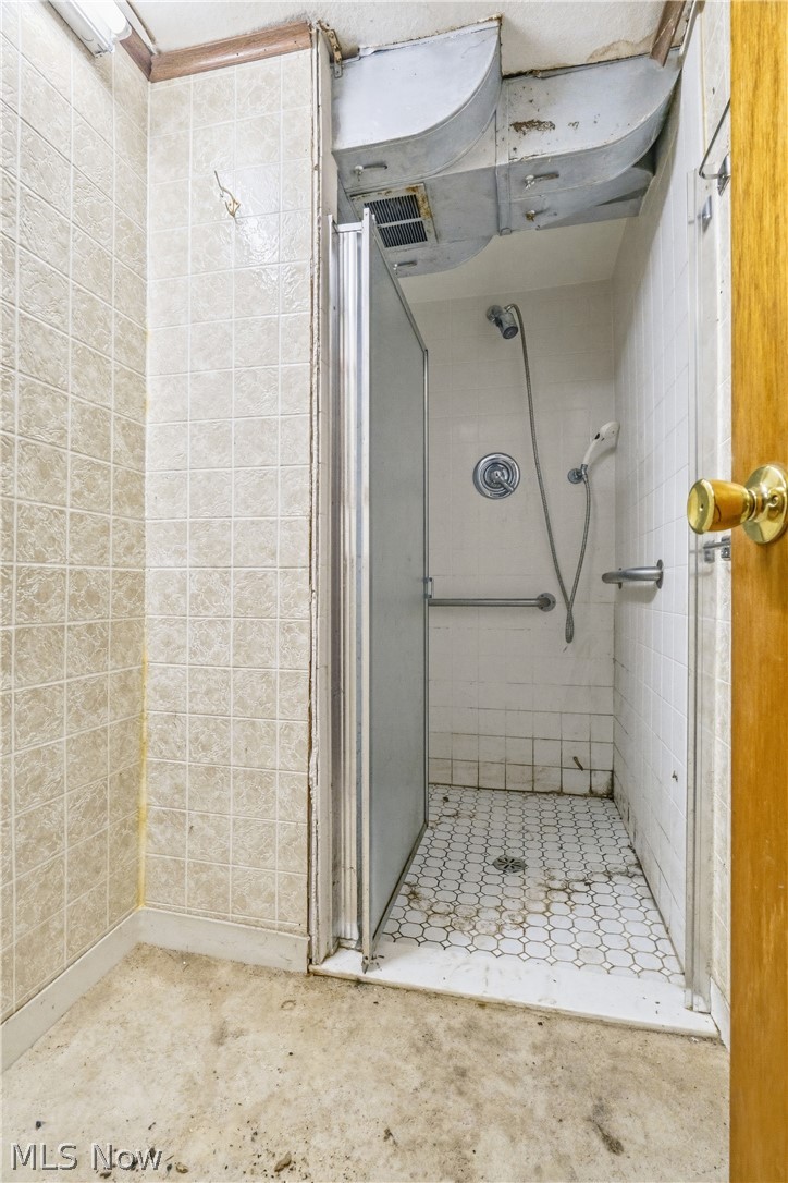 1769 Paradise Road Orrville, OH 44667 - Photo 29 of 36 Shower stall with a sliding glass door, white hex-tile flooring, and a mounted shower head with a handheld sprayer