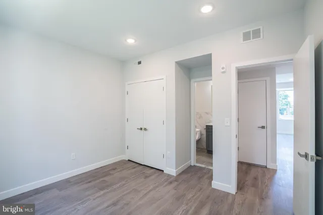 a view of an empty room with wooden floor & closet