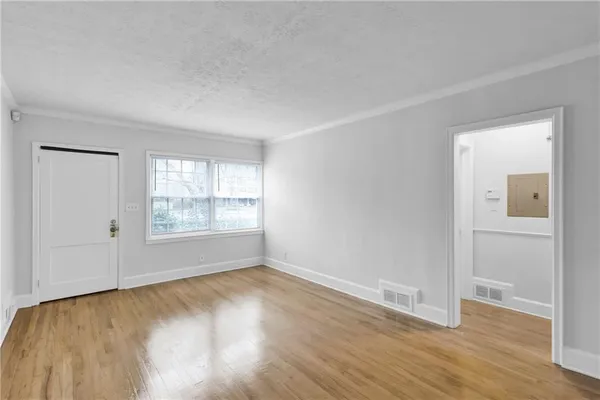 an empty room with wooden floor and windows