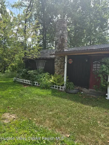 a view of a backyard with plants and large trees