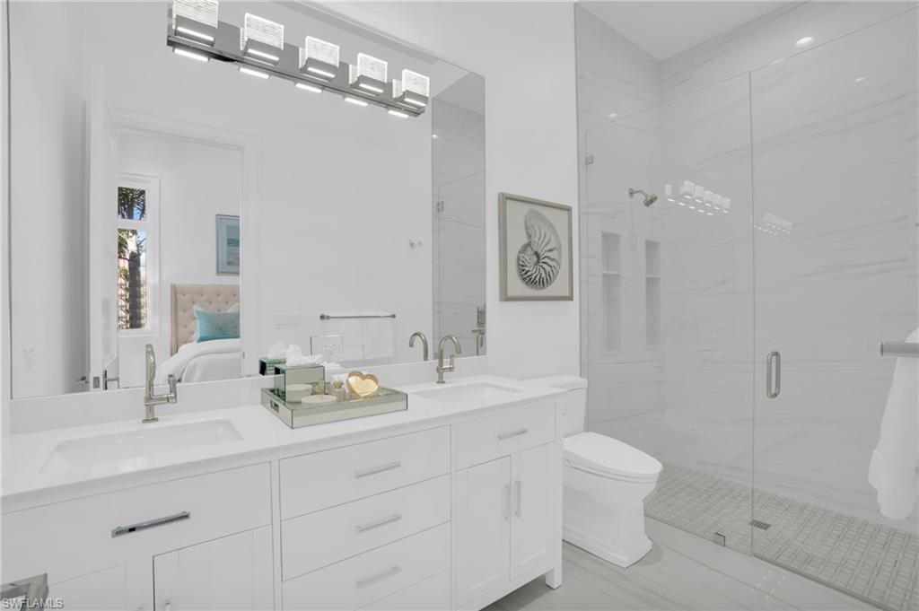 3110 Leeward Lane Naples, FL 34103 - Photo 25 of 50 a bathroom with a double vanity sink mirror and toilet