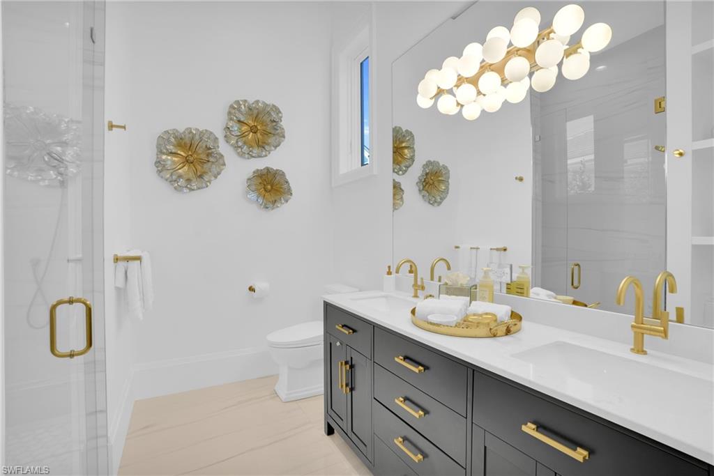 3110 Leeward Lane Naples, FL 34103 - Photo 27 of 50 a bathroom with a granite countertop sink a toilet and a mirror