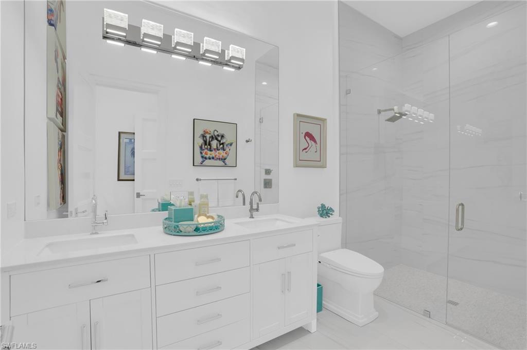 3110 Leeward Lane Naples, FL 34103 - Photo 30 of 50 a bathroom with a double vanity sink mirror and toilet