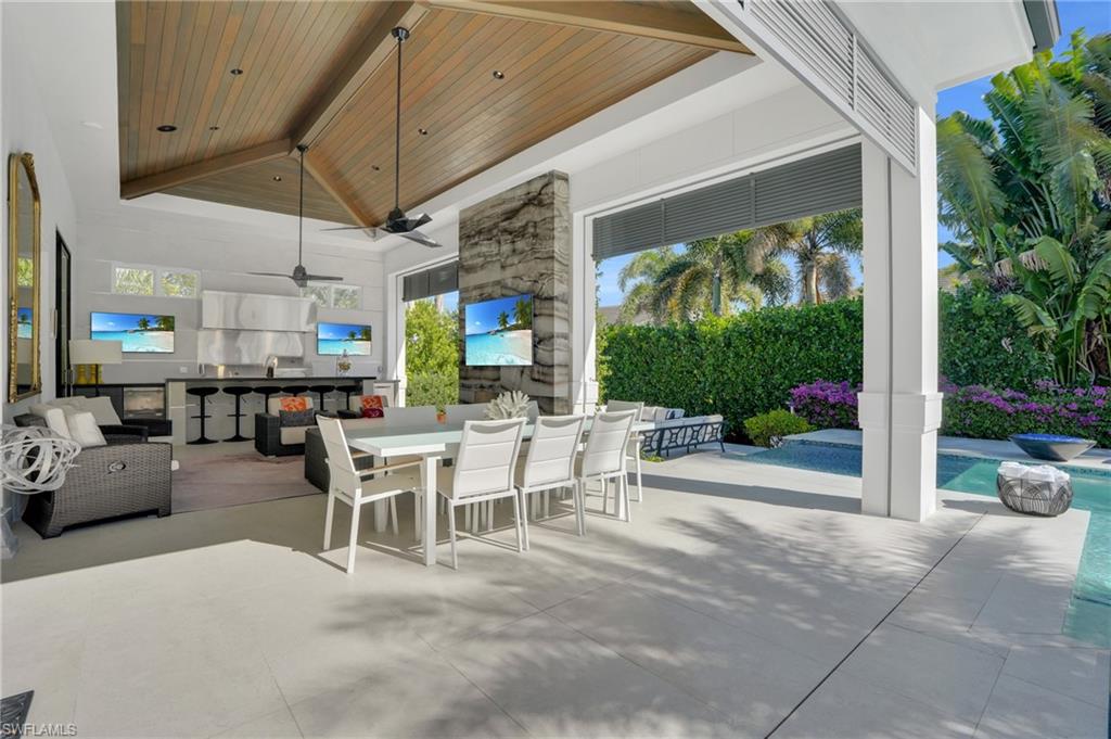 3110 Leeward Lane Naples, FL 34103 - Photo 34 of 50 a view of a patio with a dining table and chairs under an umbrella