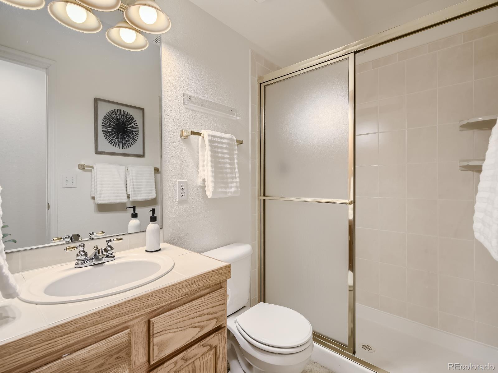 7400 West Grant Ranch Boulevard, Unit 60 Denver, CO 80123 - Photo 24 of 36 a bathroom with a sink toilet a mirror and shower