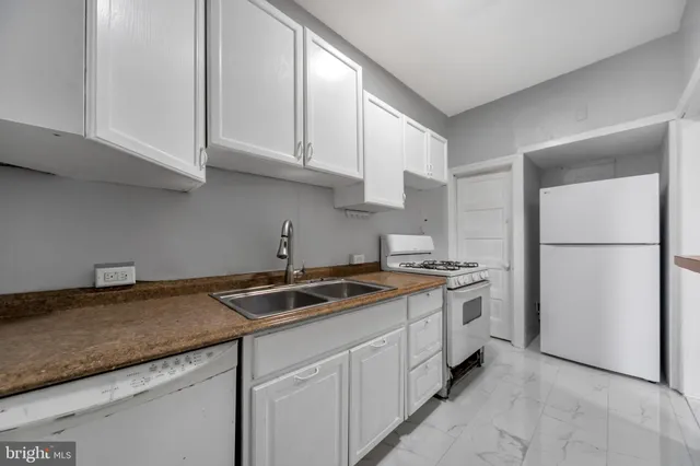 a kitchen with granite countertop a sink stove and refrigerator