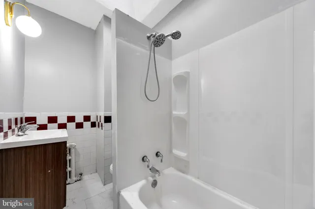 a bathroom with a tub sink vanity and shower