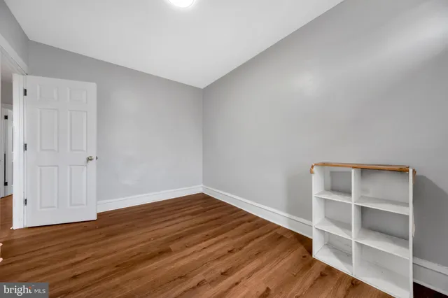 a view of an empty room with wooden floor and closet