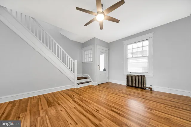 a view of empty room with wooden floor and fan